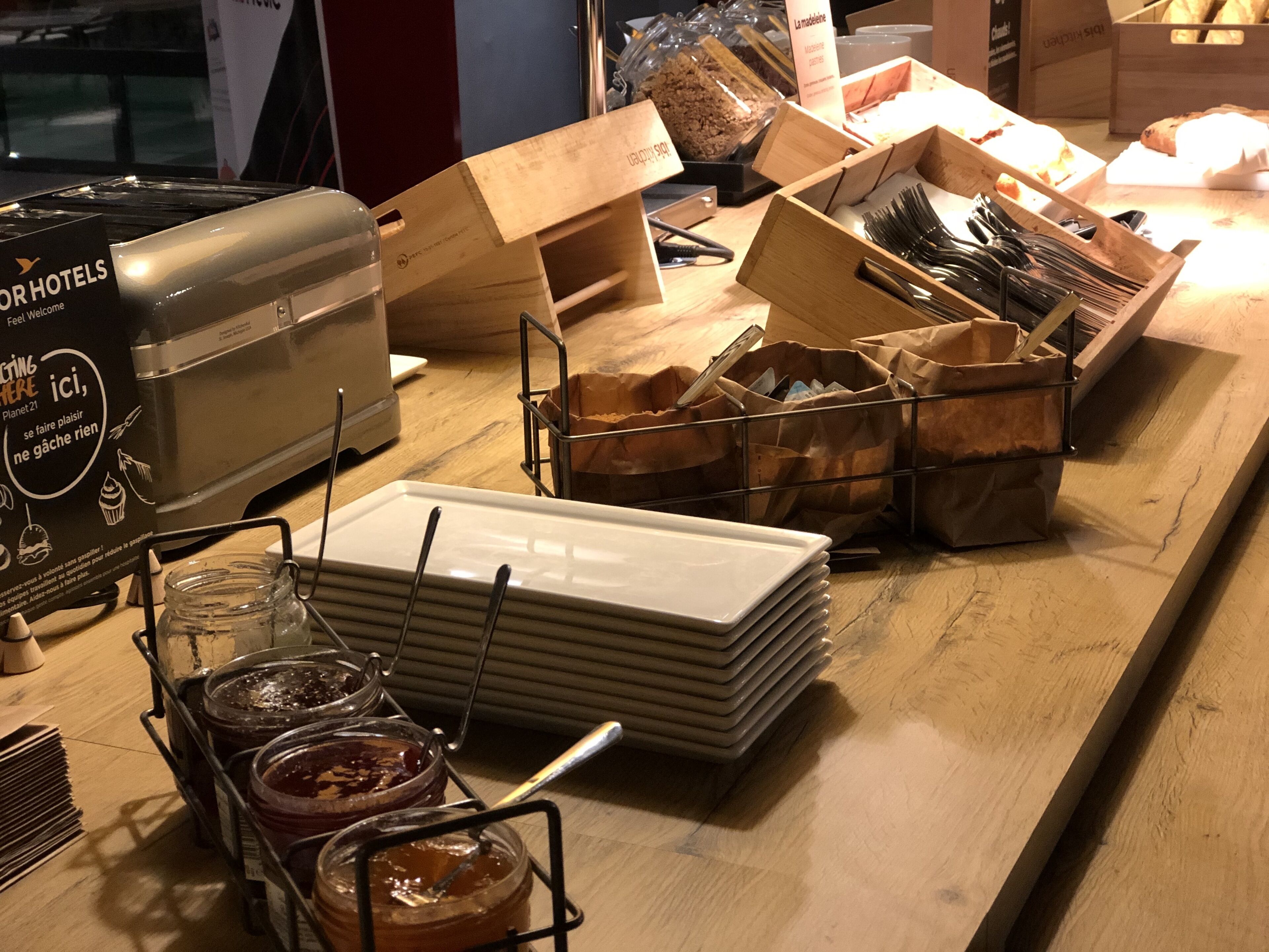 A kitchen counter with a toaster, jars of jam, and stacks of plates.
