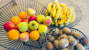 Three wire baskets containing apples, oranges, bananas, and kiwis.