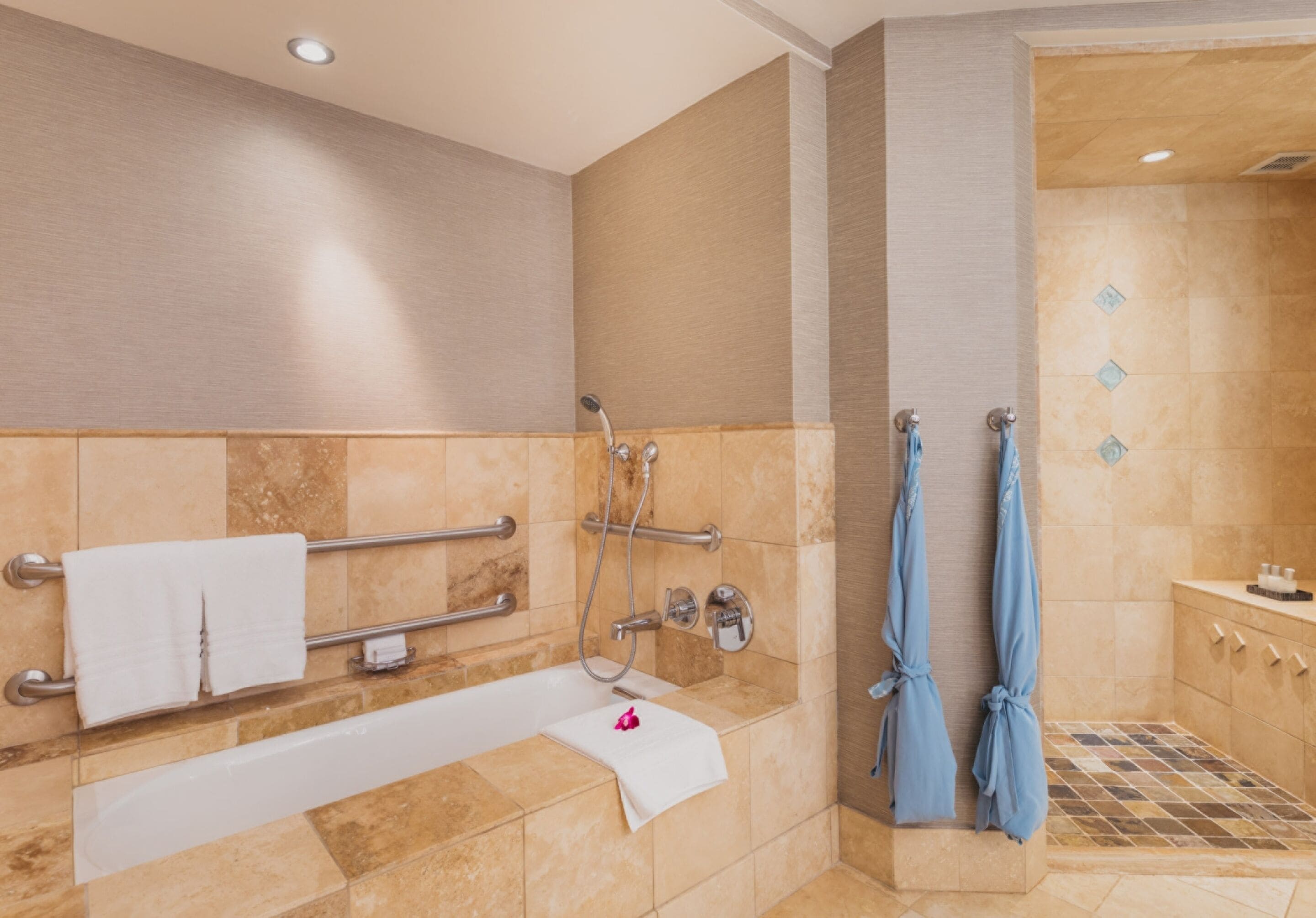 Ein modernes Badezimmer mit Badewanne, Dusche und Handläufen.