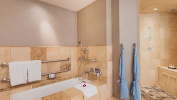 Ein modernes Badezimmer mit Badewanne, Dusche und Handläufen.
