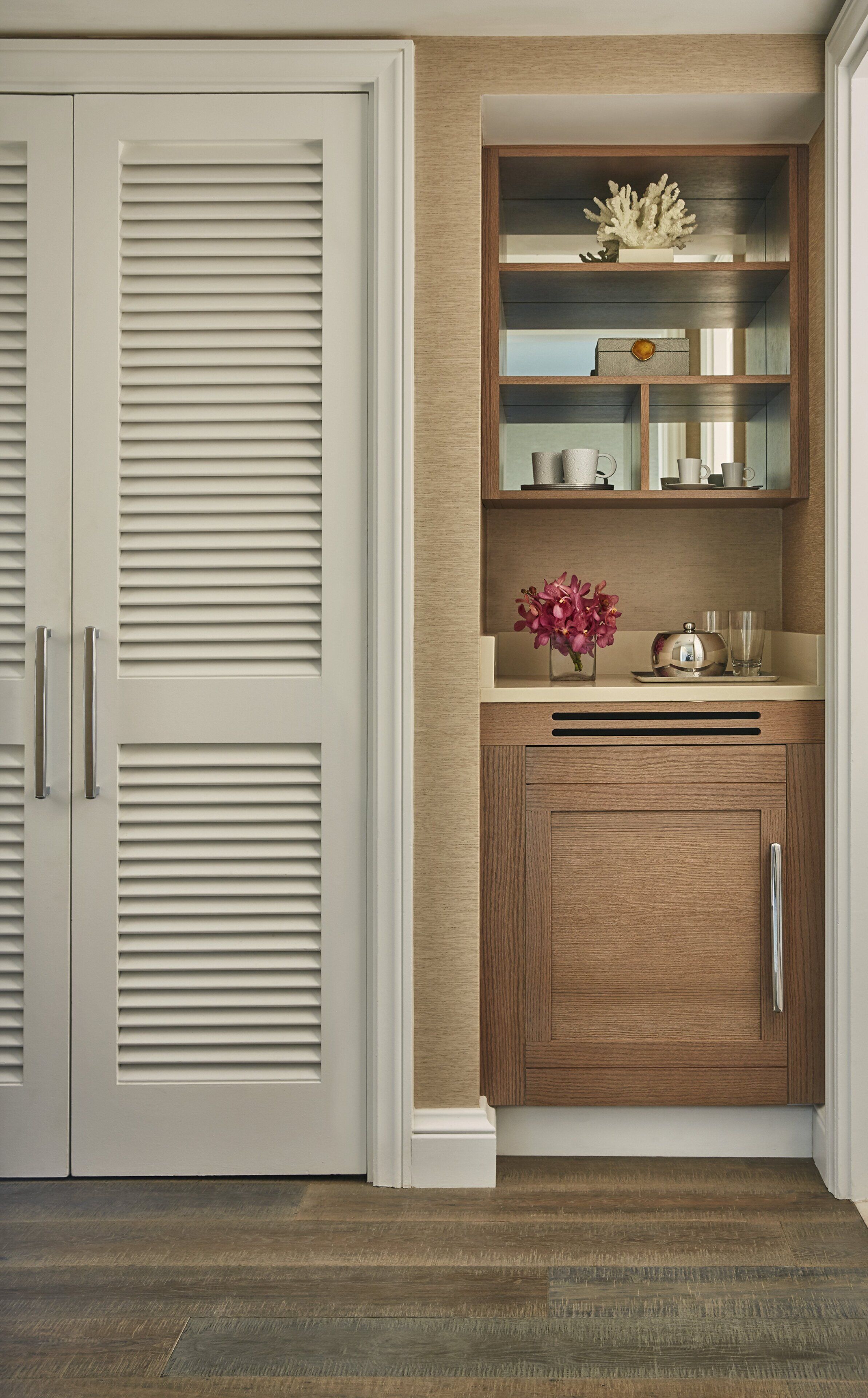 Un armario abierto con un mueble de madera y una puerta blanca con listones horizontales.