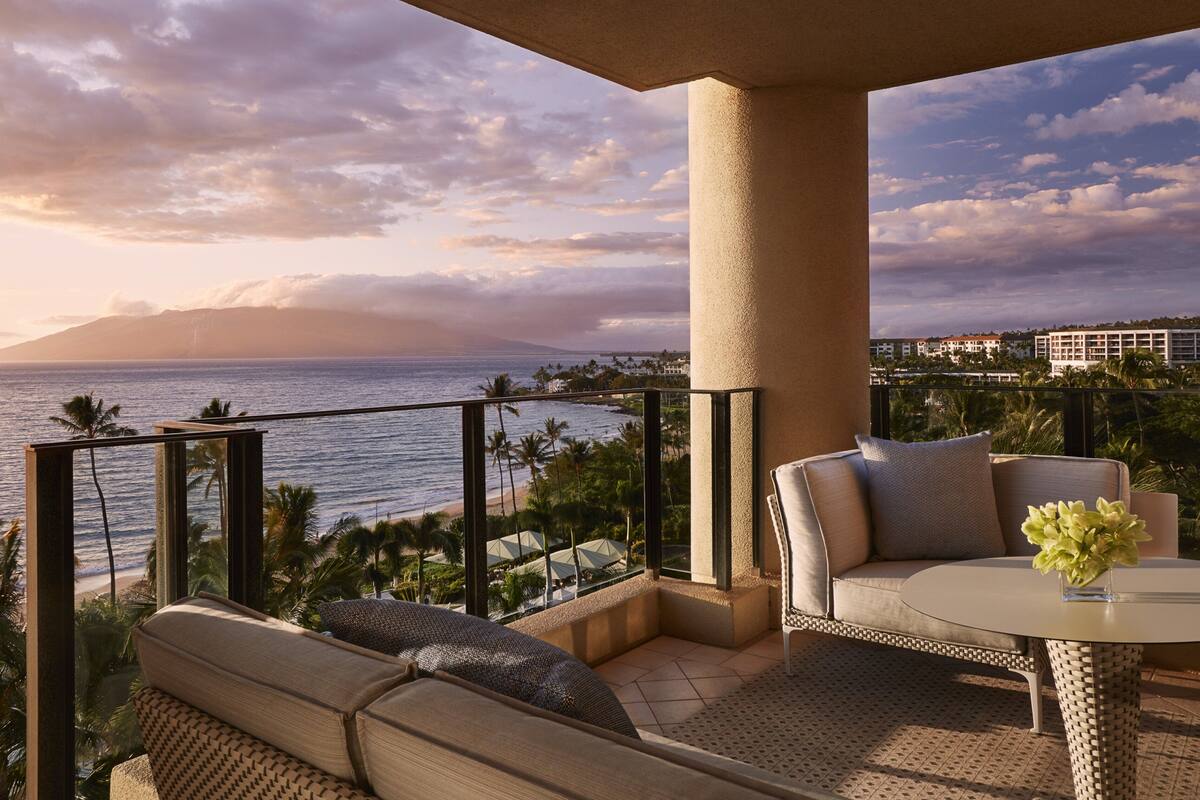 Un balcon avec vue sur l’océan, un canapé, une table avec un vase et une rambarde.