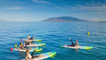 A group of people on surfboards in a calm body of water with a mountain in the background.