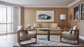 A living room with a beige sofa, two wooden chairs, a coffee table, and a patterned rug.