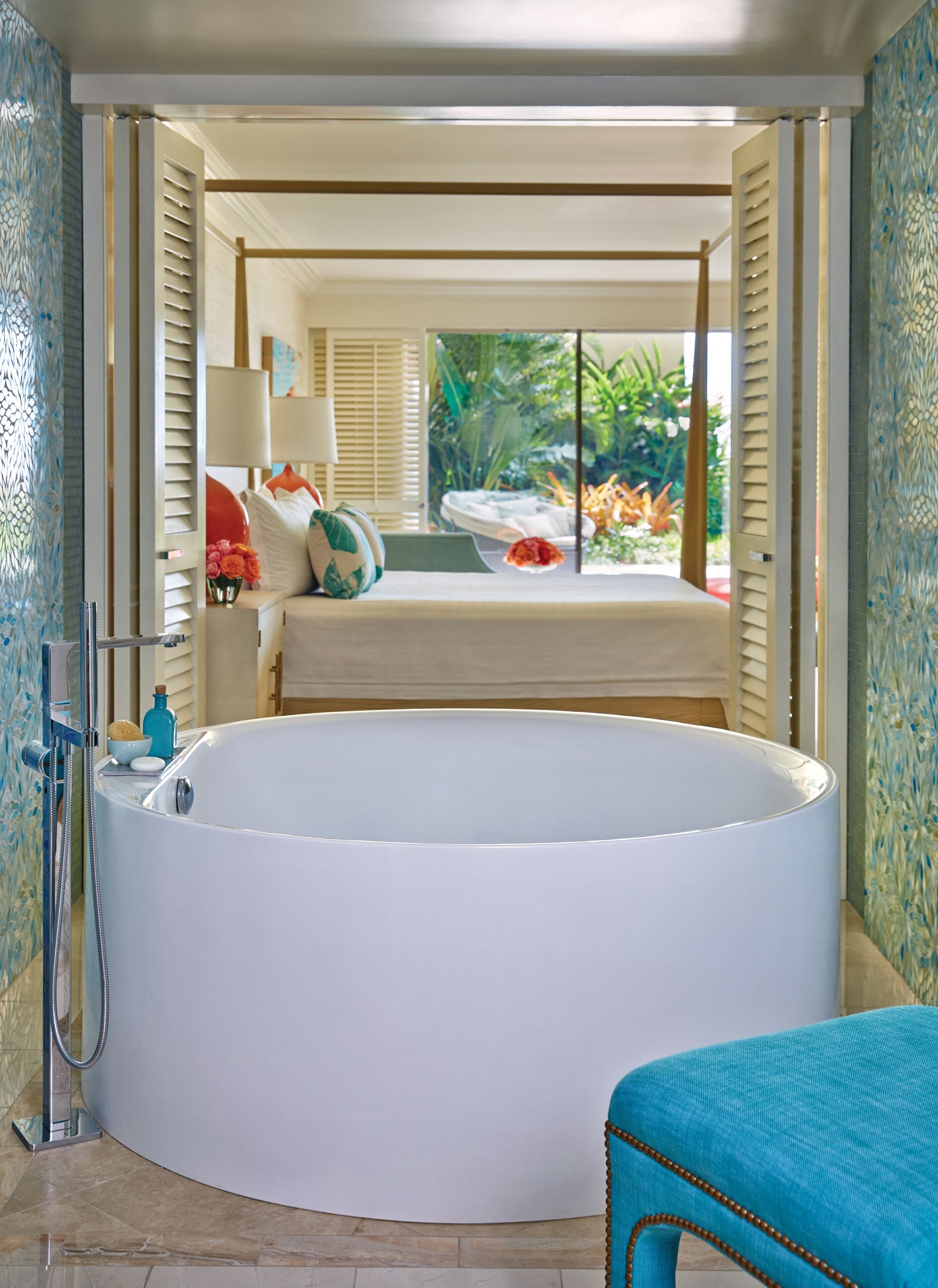 A bathroom with a large bathtub, a shower, and a sink. There is a window with a view of greenery outside.