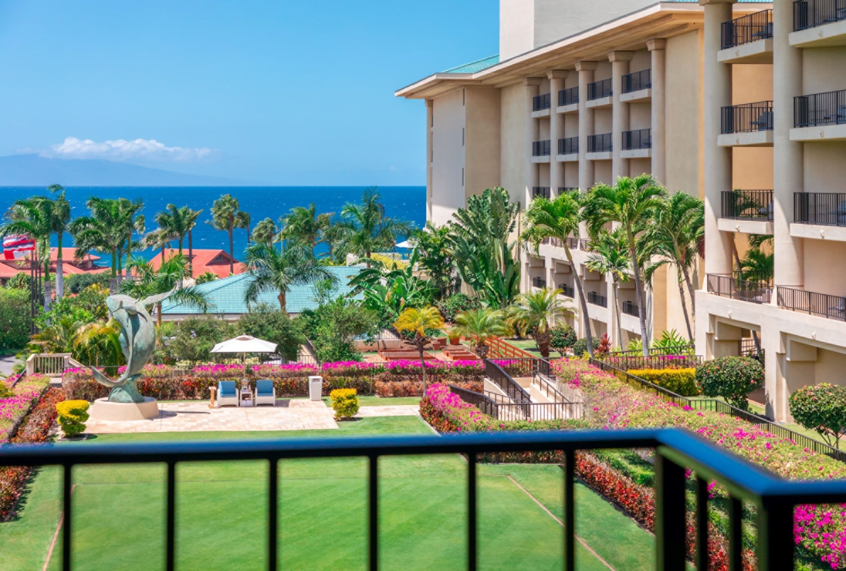 A hotel with a pool, palm trees, and a view of the ocean.