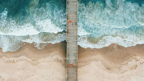 A wooden pier extending into a beach with waves crashing at the end. - Staybridge Suites Oxnard River Ridge by IHG (Oxnard)
