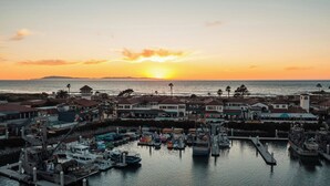 A marina with boats docked, a sunset in the background, and buildings with a coastal view. - Staybridge Suites Oxnard River Ridge by IHG (Oxnard)