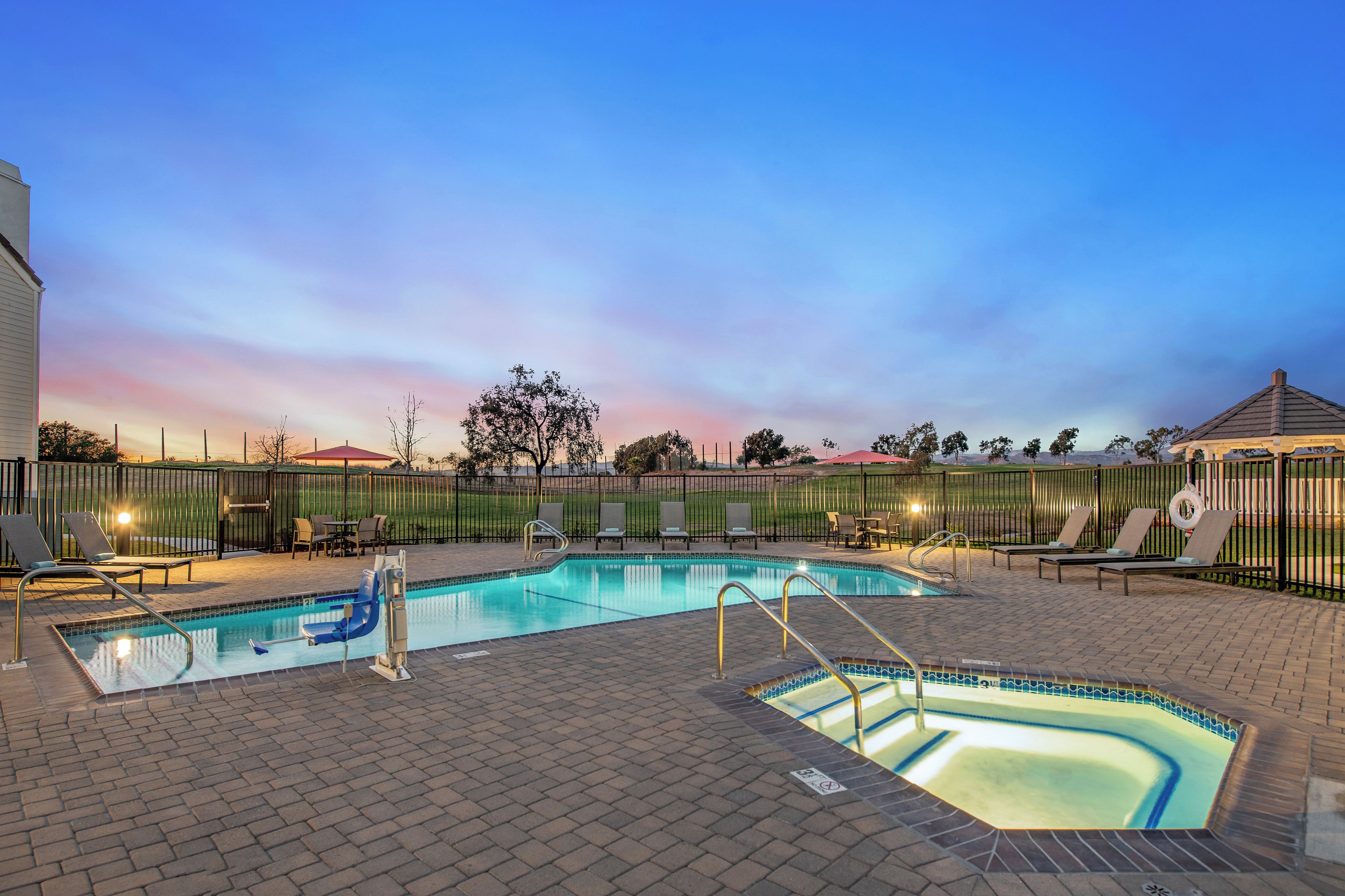 A swimming pool with lounge chairs and a fenced area.