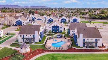 Residential townhouses surround a central courtyard with a swimming pool and well-manicured lawns.