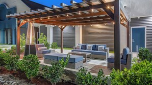 An outdoor patio with a pergola, seating area, and a heated floor. - Staybridge Suites Oxnard River Ridge by IHG (Oxnard)