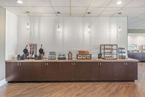 A breakfast bar with a variety of food items and appliances, including waffle makers, a coffee machine, and a display case with pastries. - Staybridge Suites Oxnard River Ridge by IHG (Oxnard)