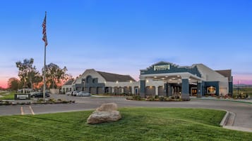 A Staybridge Suites hotel with a large parking lot, a flagpole with the American flag, and well-maintained landscaping.