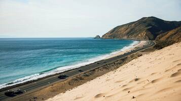 Una carretera costera con una playa y una montaña al fondo.