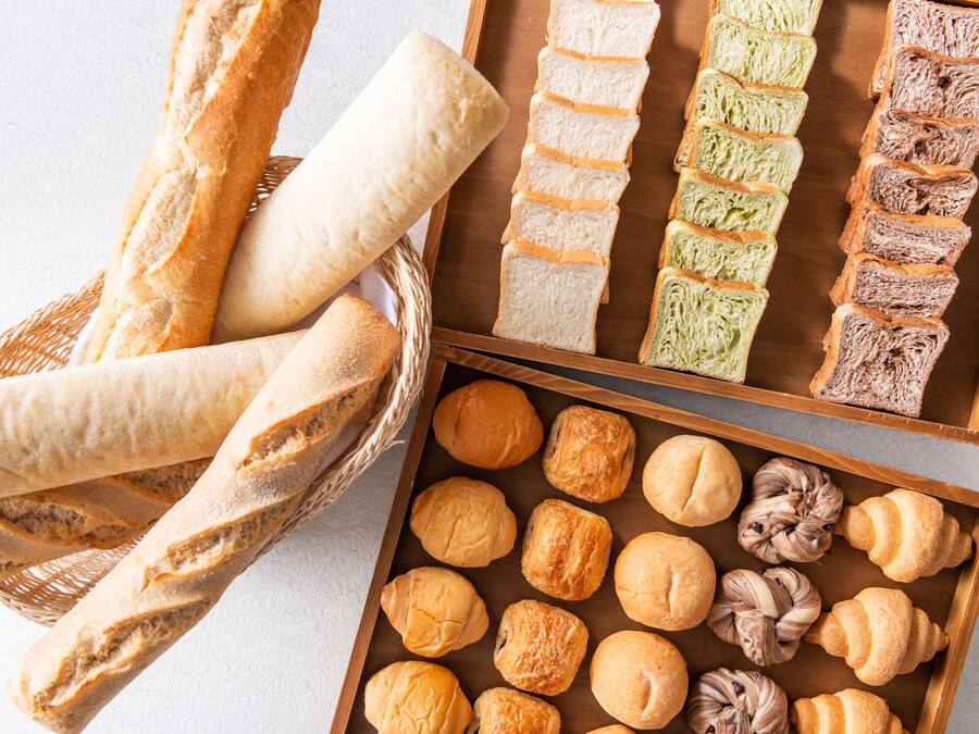 Variedad de panes y pasteles exhibidos en cestas y bandejas.