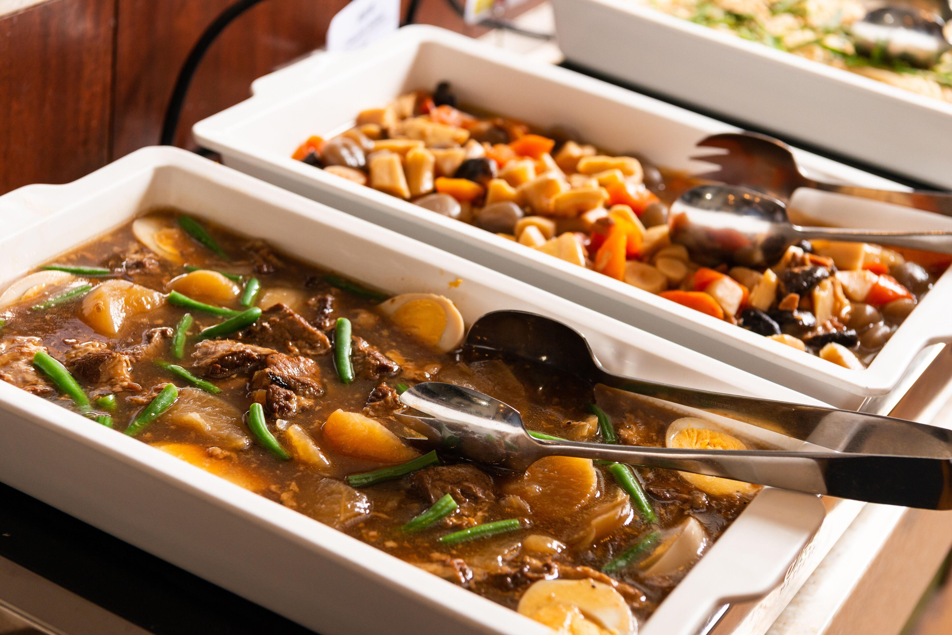 A buffet with various dishes including a beef stew and a vegetable casserole.