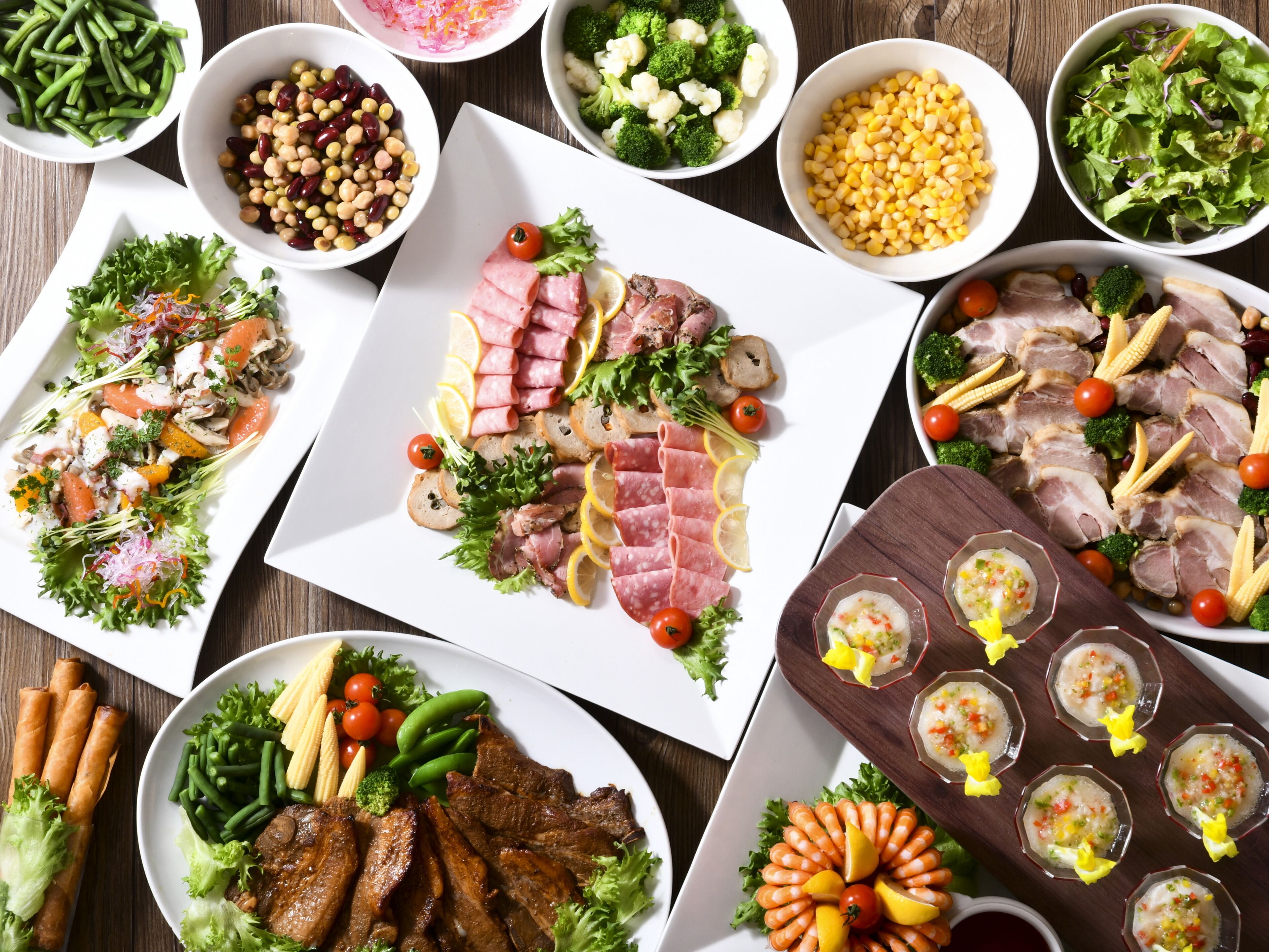 A variety of food items arranged on a table, including meats, vegetables, and salads.