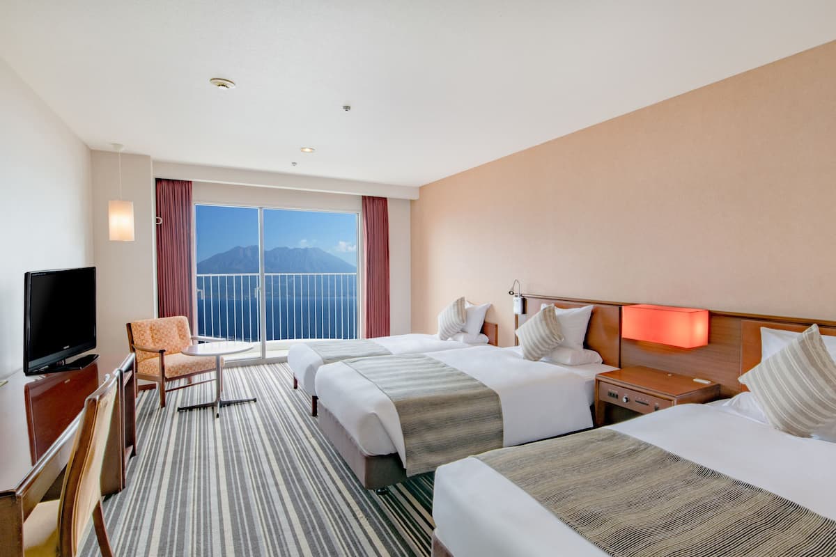A hotel room with two beds, a TV, a desk, and a chair.
