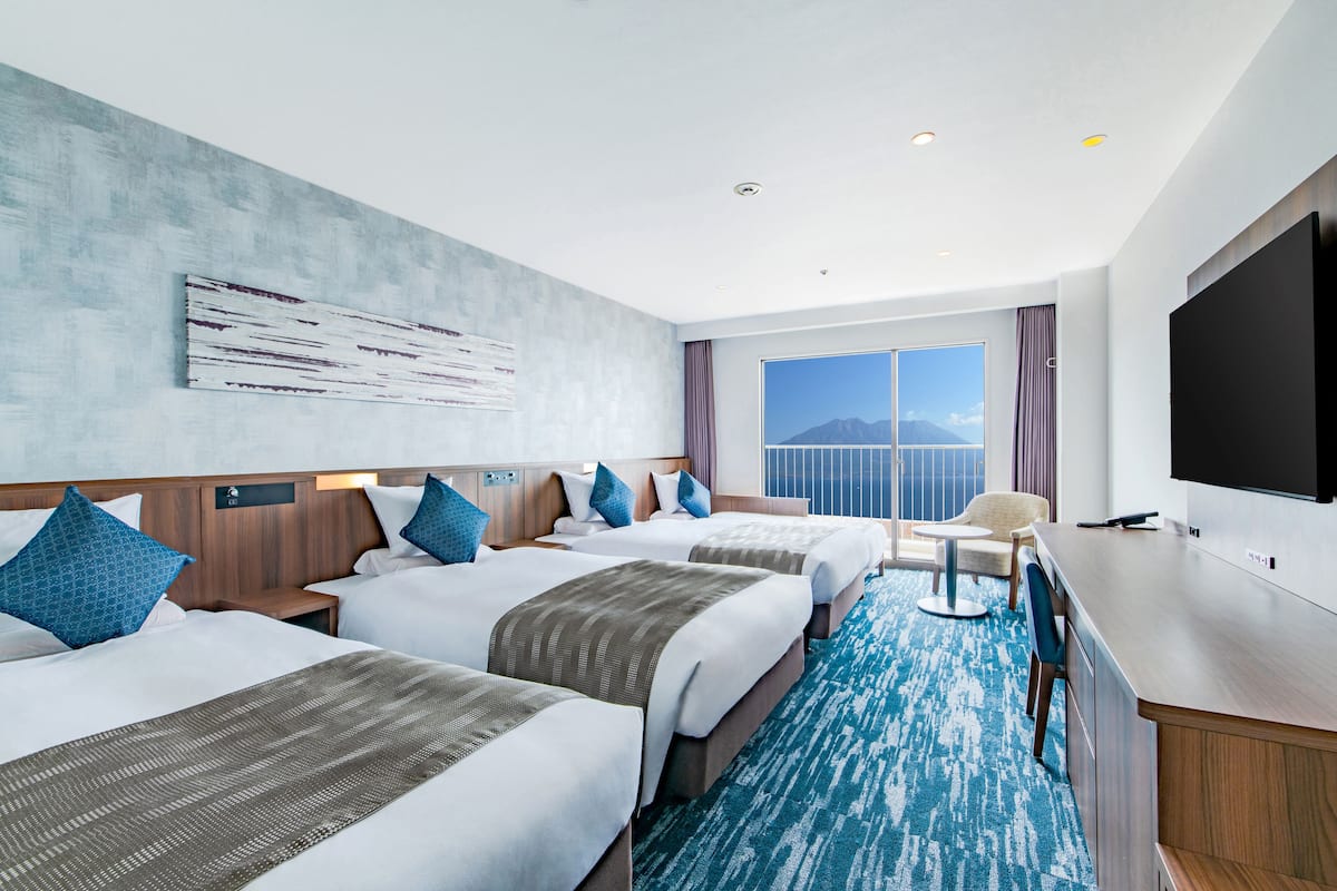 A hotel room with two beds, a TV, and a view of the mountains.