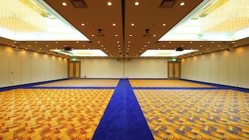 Une grande salle de conférence dotée d’un tapis à motifs, d’un éclairage encastré et d’un séparateur de tapis bleu.