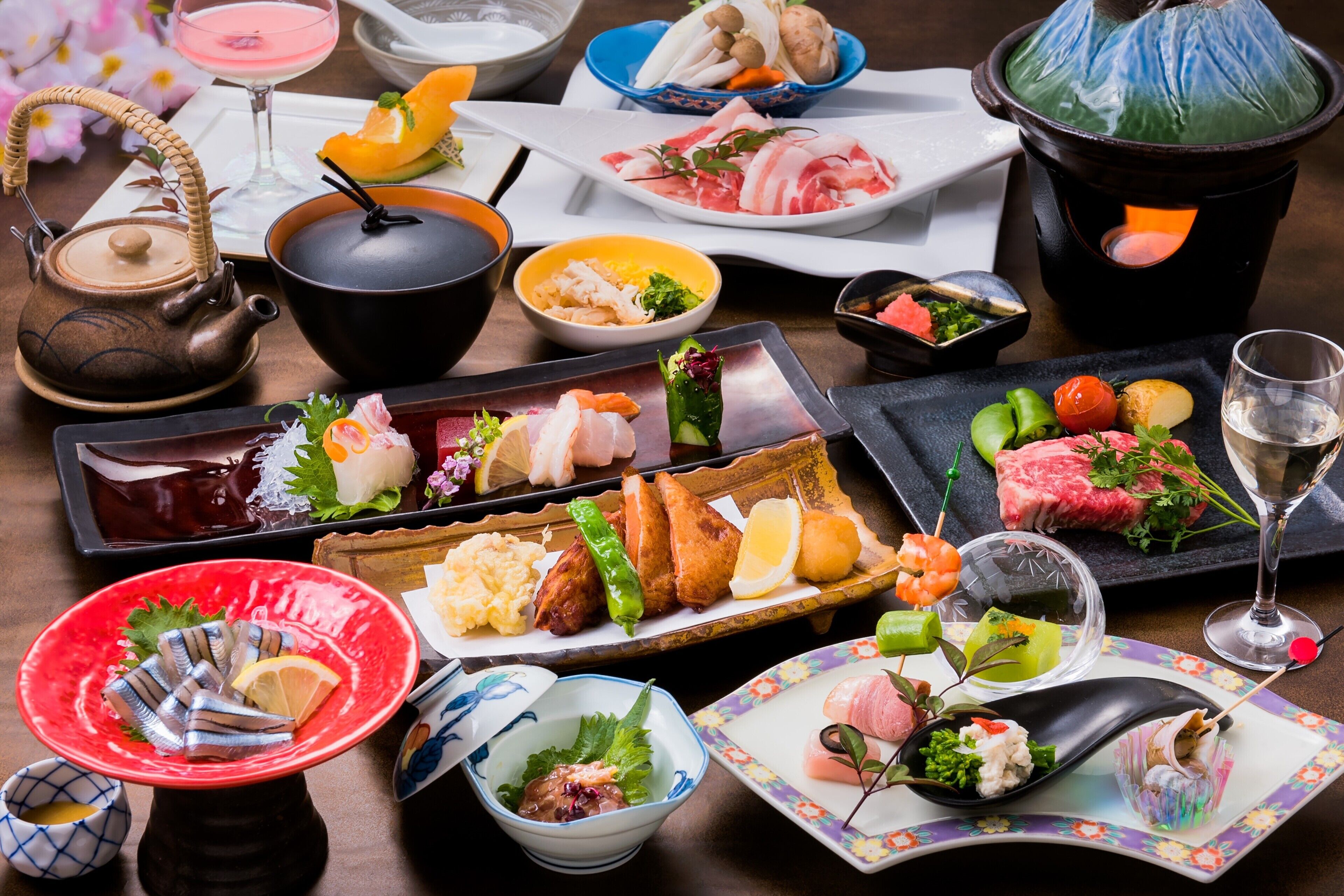 A variety of Japanese dishes, including sushi and sashimi, arranged on a wooden table.