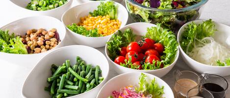 Diverse schalen met salade ingrediënten, zoals sla, tomaten, mais en bonen.