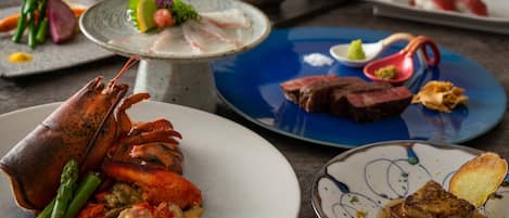 A variety of dishes including lobster, asparagus, and steak, suggesting a fine dining experience.
