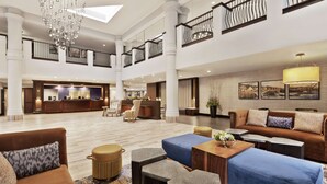 A spacious lobby with a reception desk, seating area, and a staircase. - Doubletree by Hilton McLean Tysons (McLean)