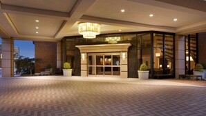 A hotel entrance with a modern design, featuring a large glass door, a chandelier, and potted plants. - Doubletree by Hilton McLean Tysons (McLean)
