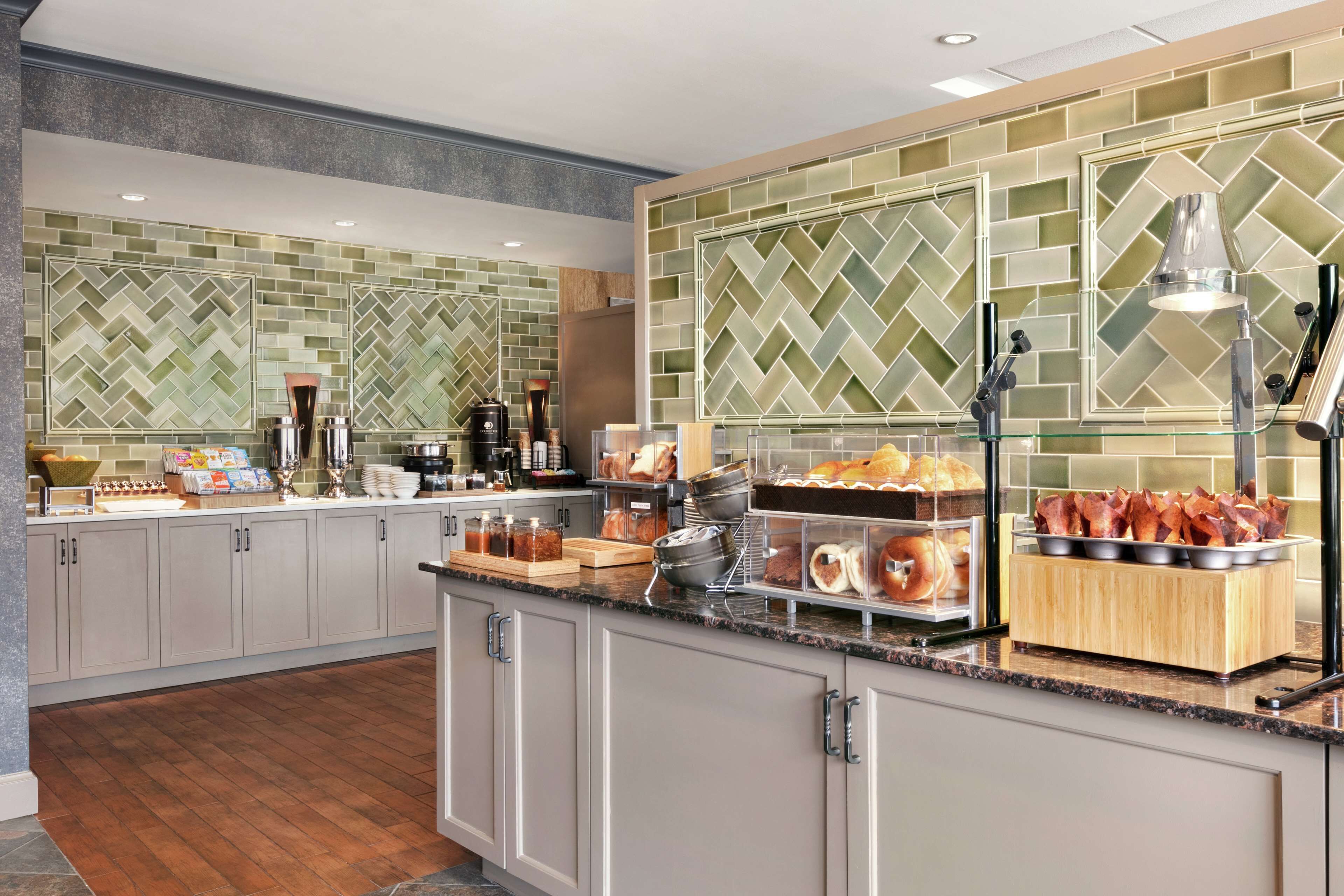 A modern kitchen with a breakfast bar, various food items, and a coffee station.