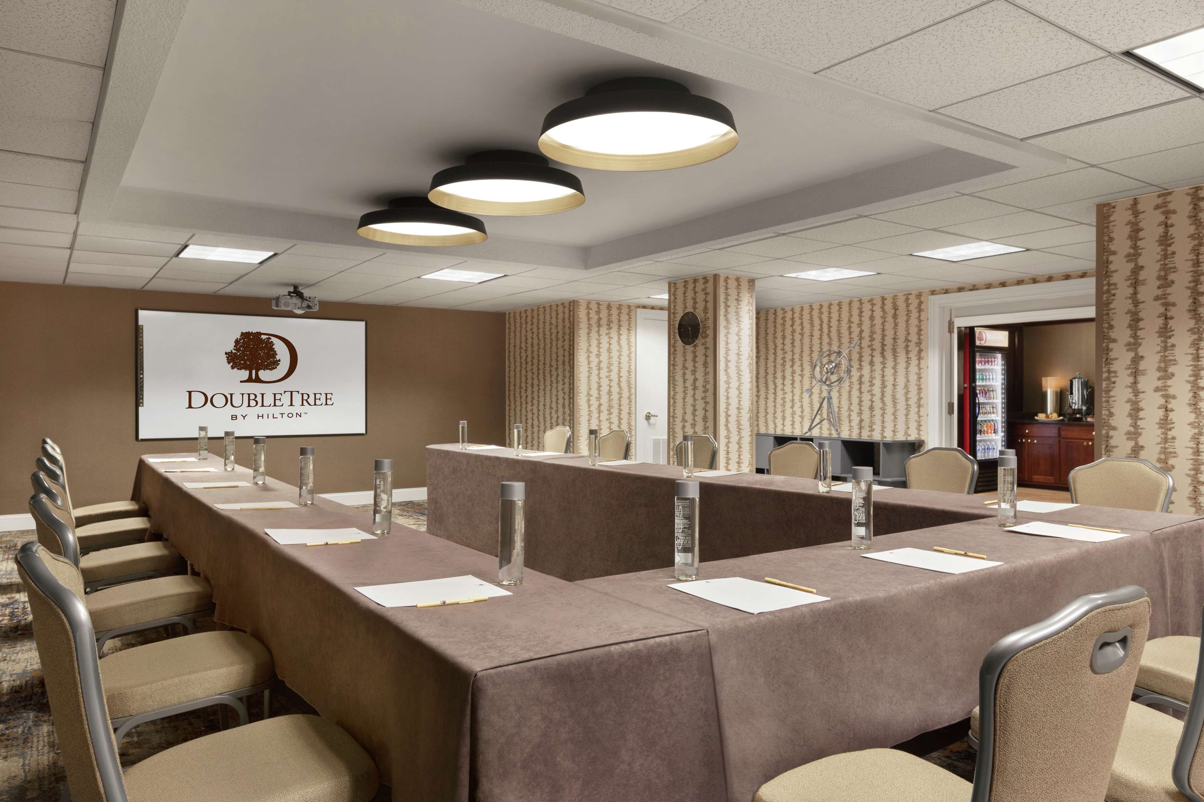 A conference room with a long table, multiple chairs, and a projector screen displaying the DoubleTree logo.