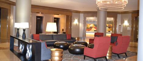 A lobby with a reception desk, seating area, and a chandelier.
