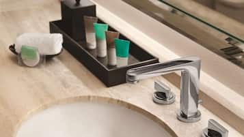 A bathroom with a modern sink, chrome faucet, and toiletries in a tray.