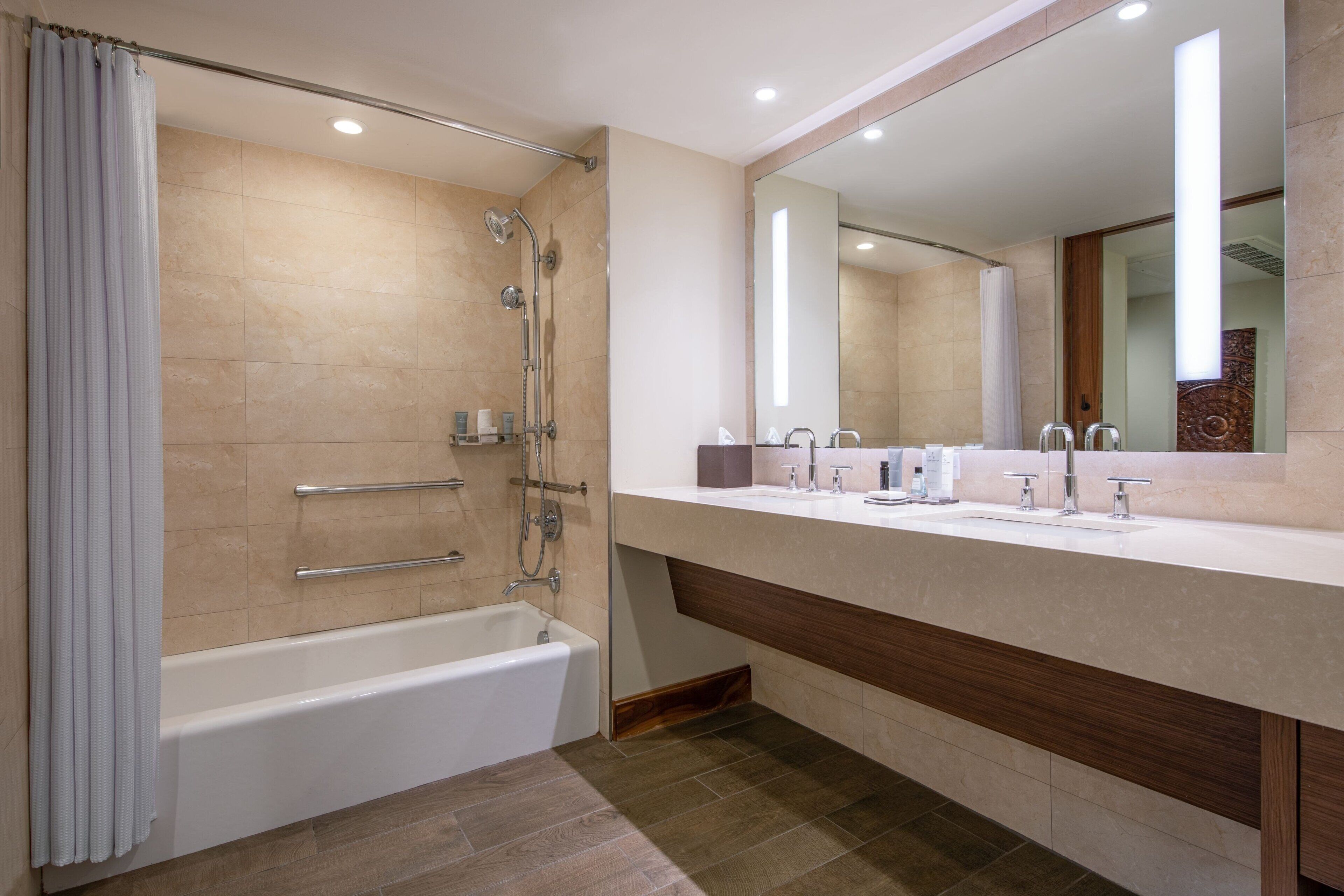Un baño moderno con bañera, ducha, tocador con espejo y lavamanos.