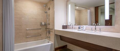 A modern bathroom with a bathtub, a shower, a vanity with a mirror, and a sink.