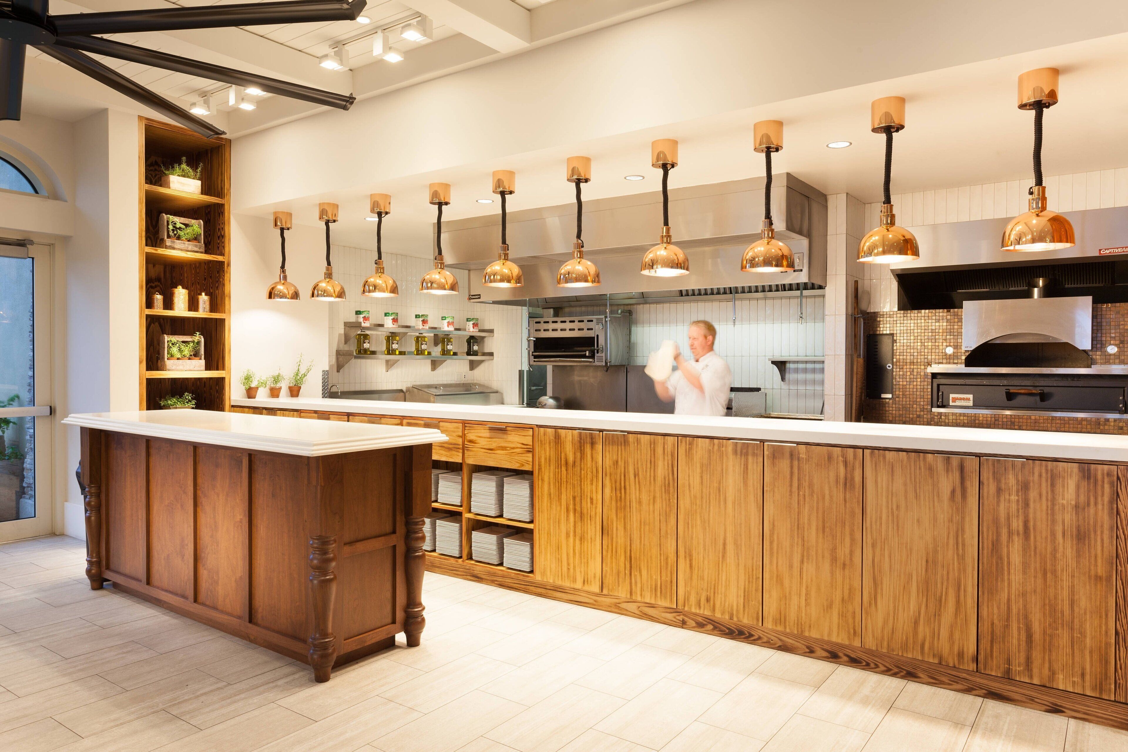 A modern kitchen with wooden cabinetry, pendant lighting, and a central island.