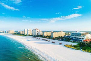 Um resort costeiro com villas na orla, uma praia arenosa e vista para o oceano.