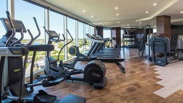 Une salle de sport équipée de tapis de course, de vélos elliptiques et de matériel de musculation.