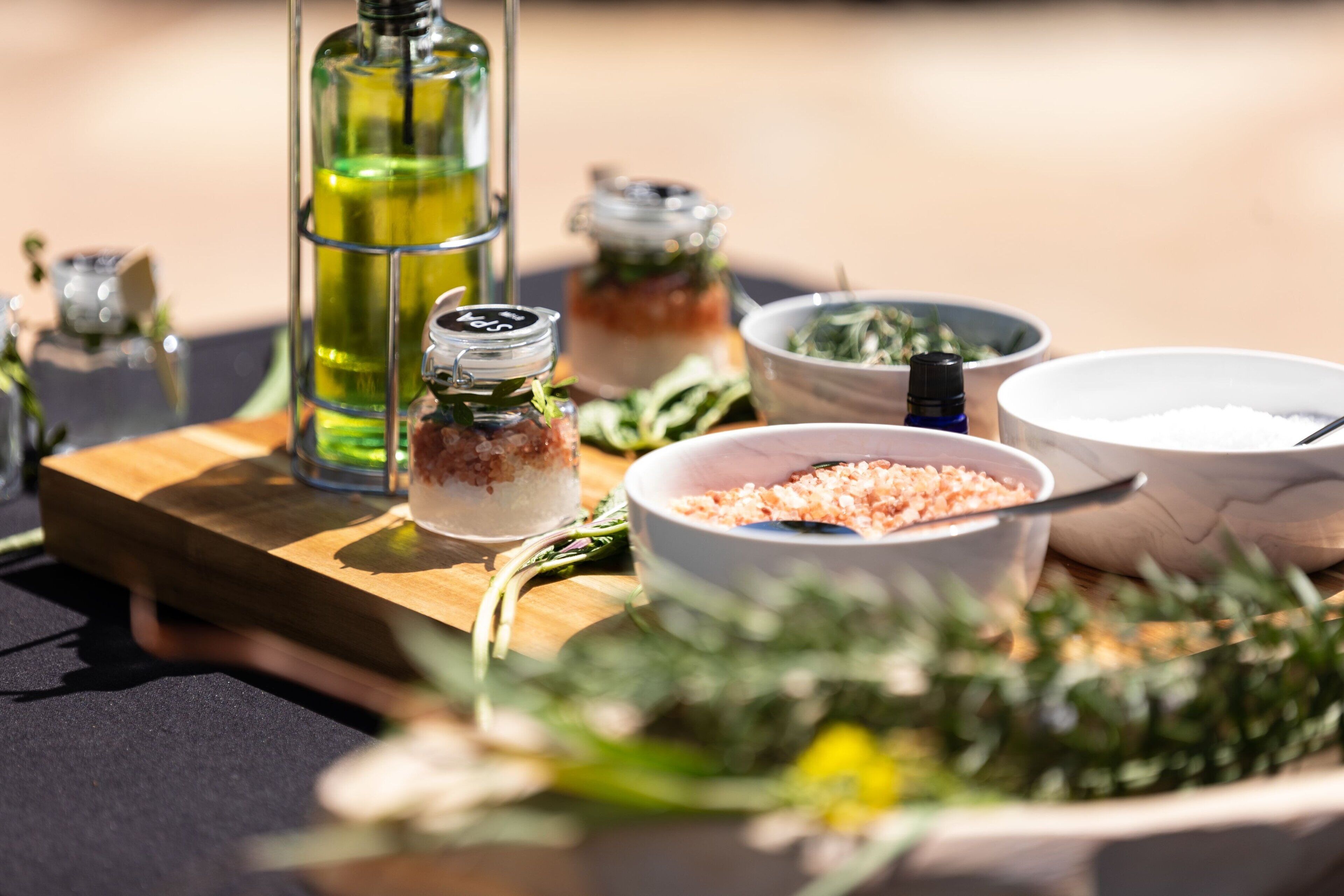 Una tabla de madera con varios utensilios de cocina, incluyendo una botella de aceite, un cuenco de sal y un tarro de especias.