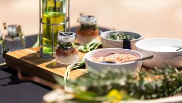 Una tabla de madera con varios utensilios de cocina, incluyendo una botella de aceite, un cuenco de sal y un tarro de especias.