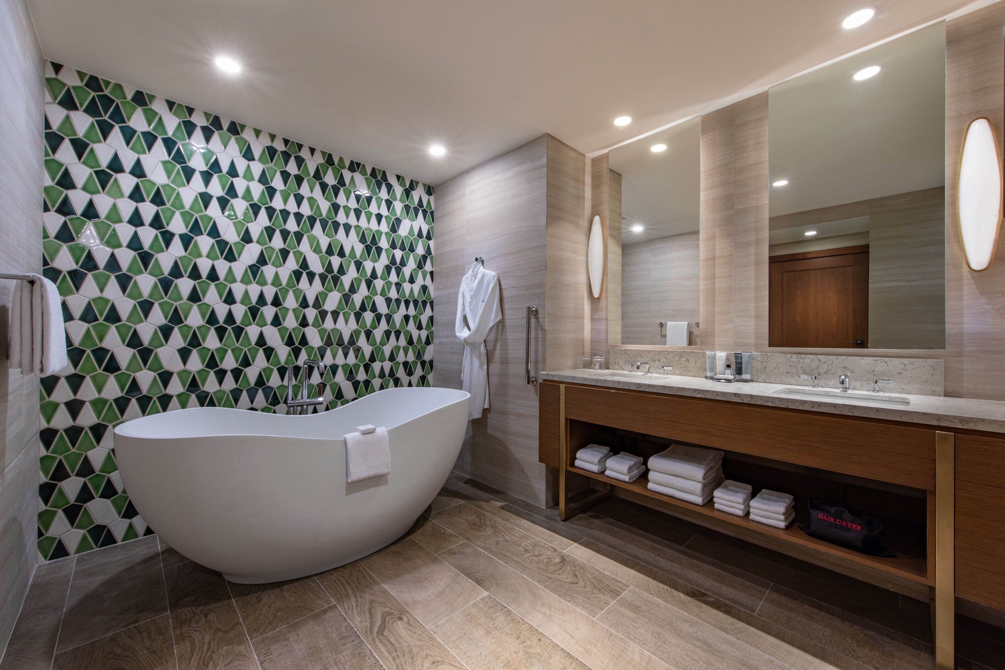 Un bagno moderno con una vasca freestanding, un grande specchio e un mobile lavabo con porta asciugamani.