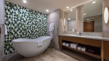 Un bagno moderno con una vasca freestanding, un grande specchio e un mobile lavabo con porta asciugamani.