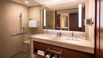 Un bagno moderno con cabina doccia in vetro, doppio lavabo e un grande specchio.
