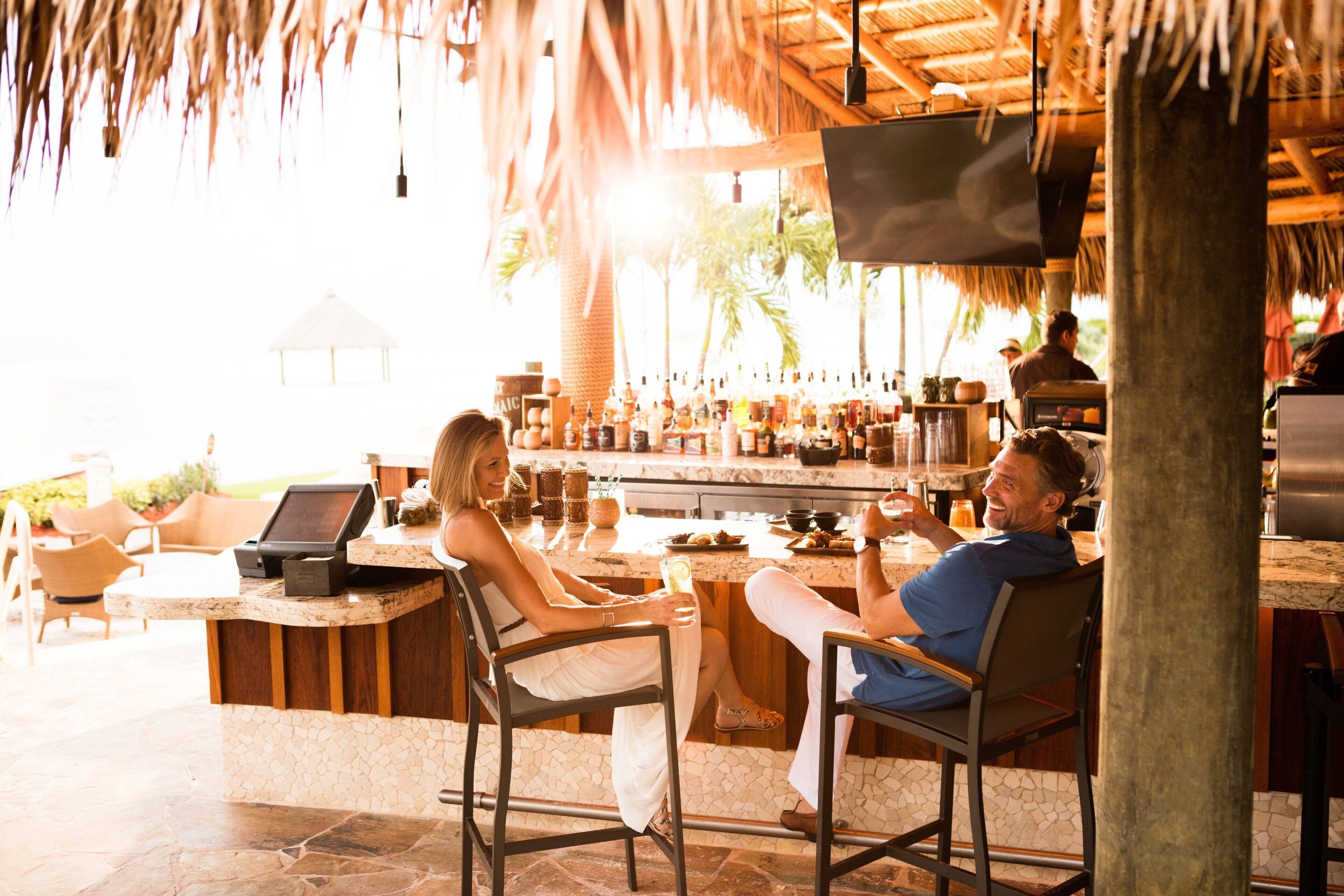 A bar area with a counter, seating, and a television screen.