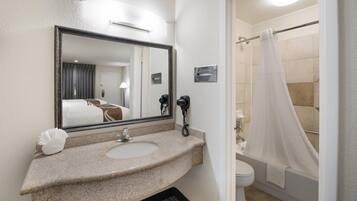 Un baño con lavamanos, espejo, inodoro y cortina de ducha.