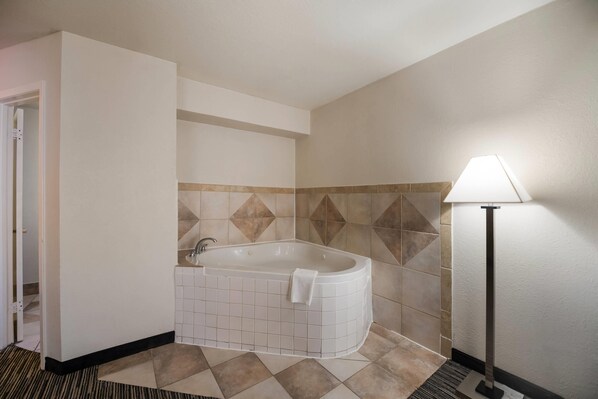 Une salle de bain avec une baignoire sur pieds, un lampadaire et un mur recouvert de carreaux.