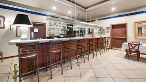 Una zona de bar con una barra alargada, varios taburetes y una máquina de café.