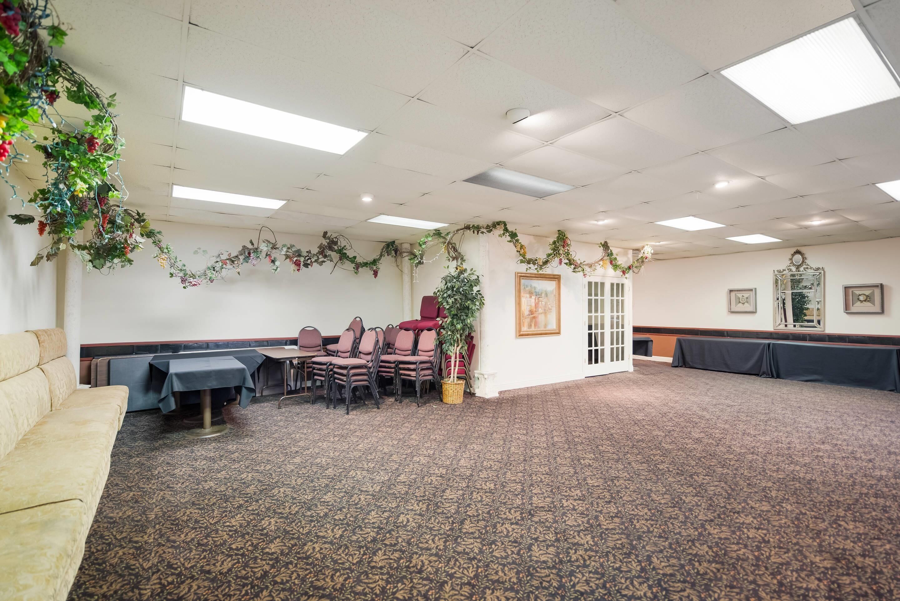 A conference room with a carpeted floor, tables, chairs, and a sofa.