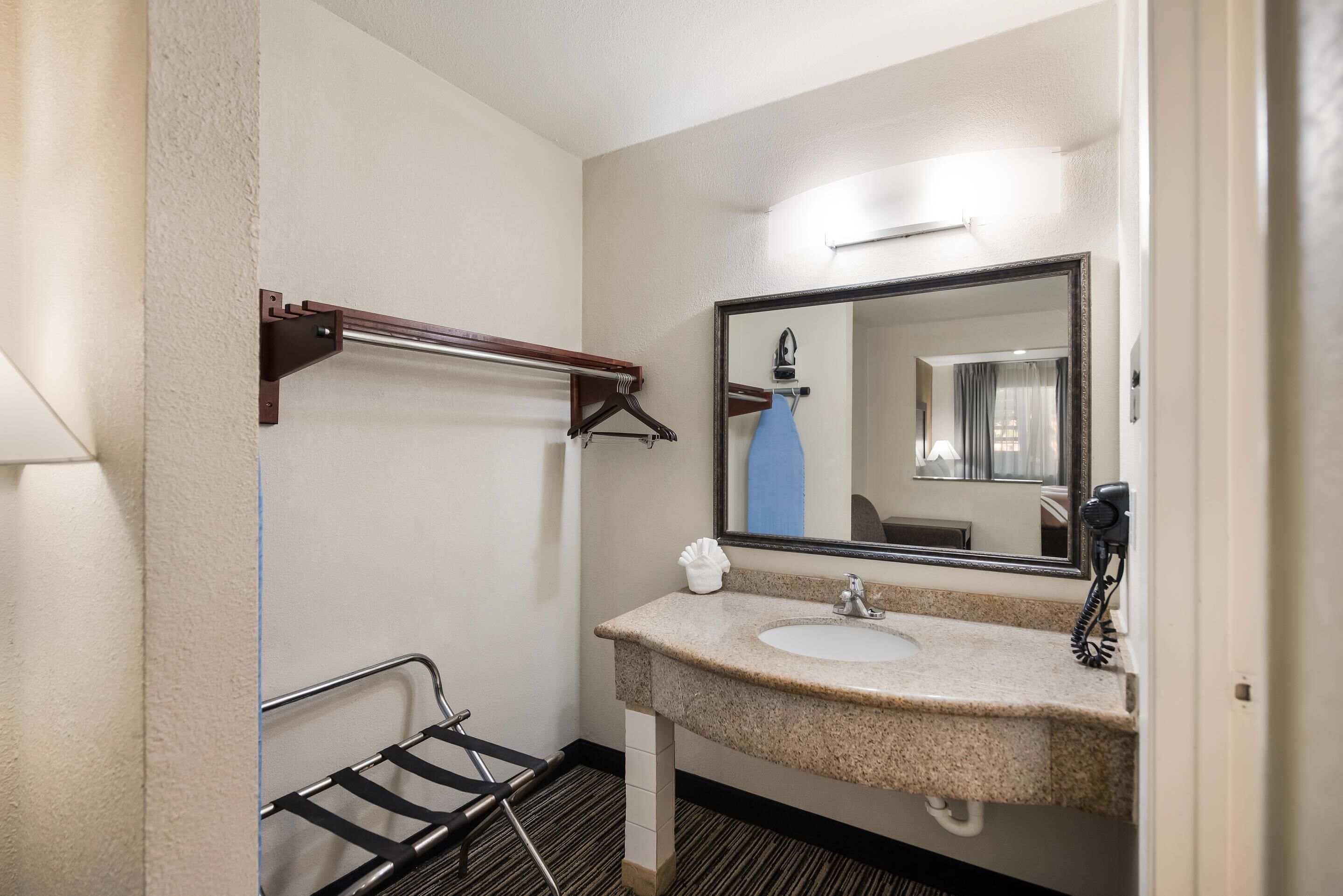 Une salle de bain d’hôtel équipée d’un lavabo, d’un miroir, d’un porte-serviettes et d’un espace douche.