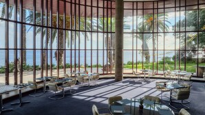 A spacious indoor area with large windows offering views of palm trees and the ocean. - Pestana Casino Park Ocean and SPA Hotel (Funchal)